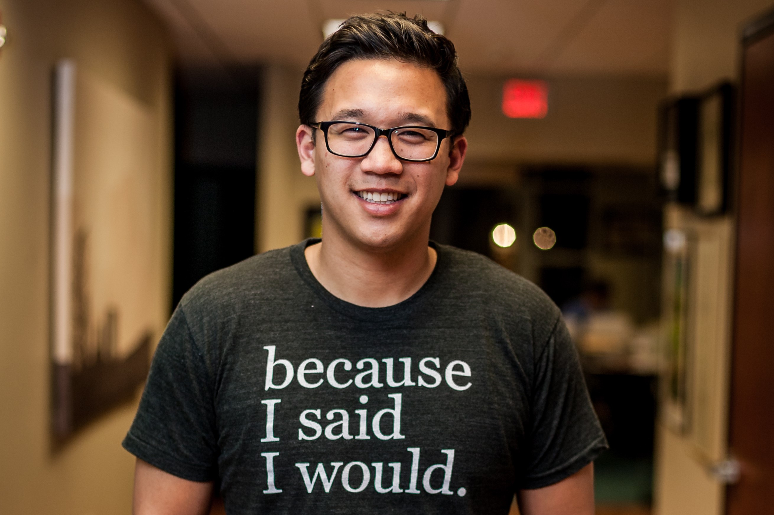 Asian man with glasses smiling wearing a shirt that reads: because I said I would.